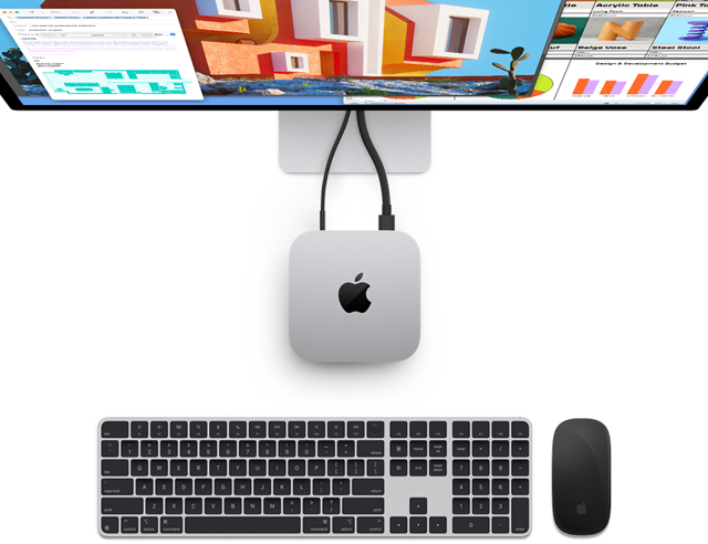 Draufsicht auf den Mac mini in Silber mit Apple Logo, angeschlossen an einen Monitor und neben einem kabellosen Magic Keyboard und einer kabellosen Magic Mouse